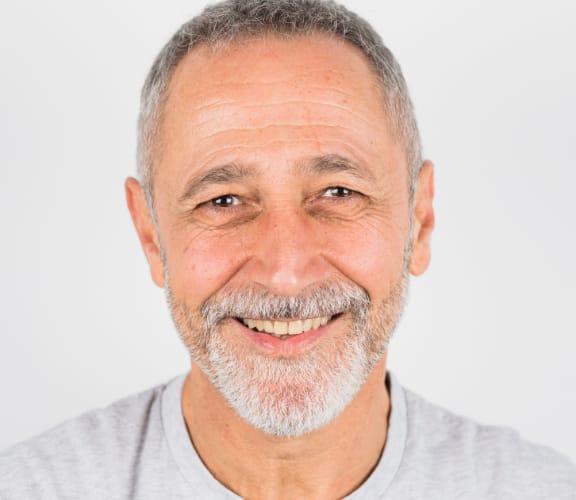 Mature man with beard smiling and showing his upper teeth